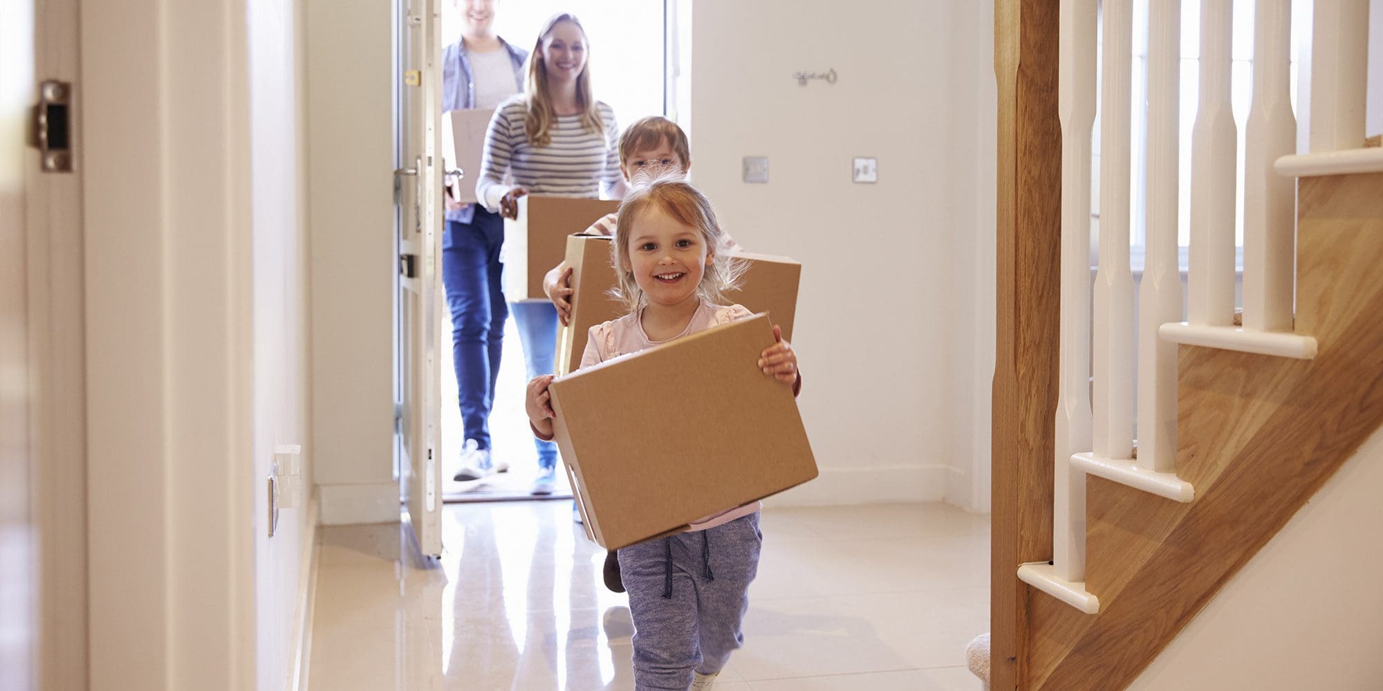 Young girl and boy carrying boxes into their new home